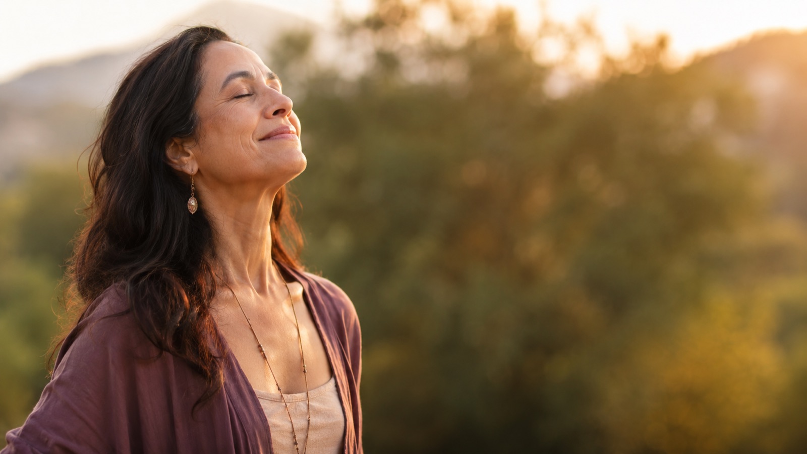 Femme apaisée respirant au coucher du soleil